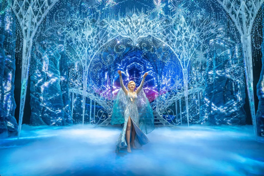 Musical Disneys Die Eiskönigin in Hamburg – Elsa im Eispalast im langen Kristallkleid vor großer Freitreppe und Bögen aus Eiskristall